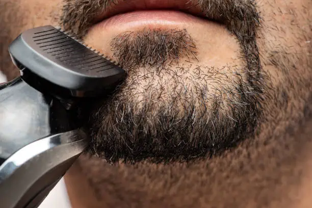 Man trimming goatee in close up