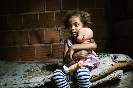 Brazilian little girl holding a doll in the bedroom. Rio de Janeiro State, Brazil.