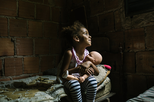 Brazilian little girl holding a doll in the bedroom. Rio de Janeiro State, Brazil.