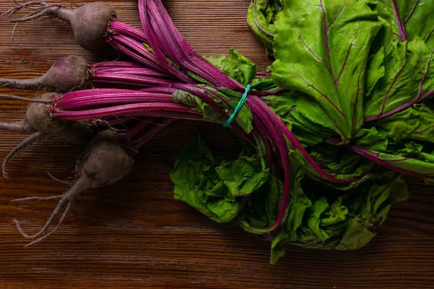 Red organic bunch Beetroot with herbage green leaves with foliage, on wooden background. Detox