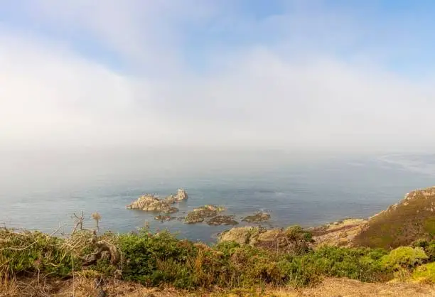 The cliffside at Noirmont Point in Jersey, Channel Islands.  A sea mist rolls in towards the offshore rocks