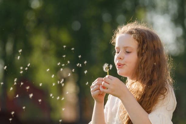 istock Cute curly girl blowing dandelion in sunset light. 1018975754