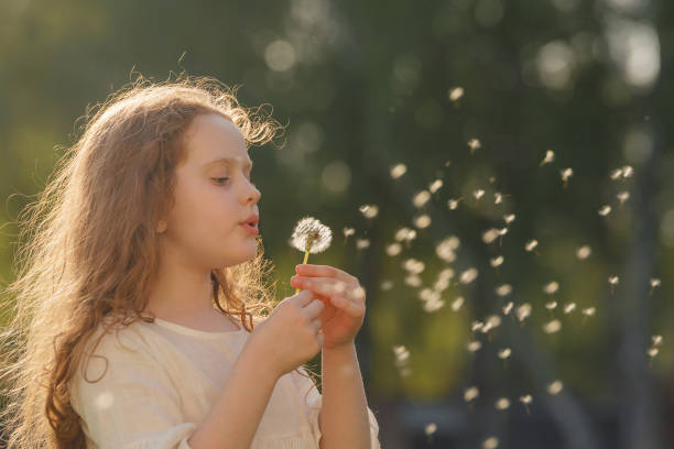 istock Cute curly girl blowing dandelion in sunset light. 1018976054