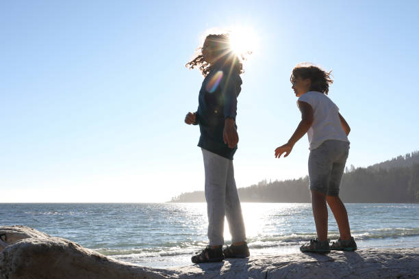 istock Two girls play on log, at beach 1018976062