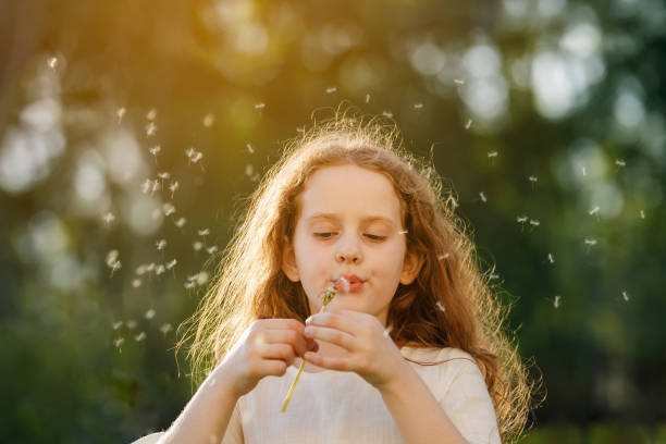 istock Cute curly girl blowing dandelion in sunset light. 1018976102