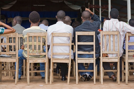 Scene from behind of men sitting in chairs at church service Bujumbura Burundi
