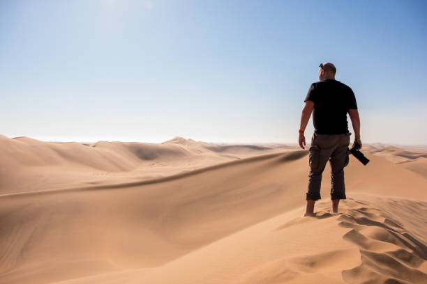 istock photographer stood on top of a sand dune in Namibia 1018991006