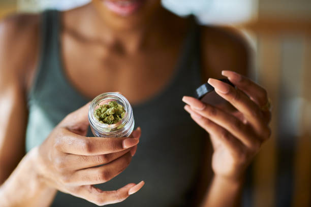 african american woman opening bottle of weed close up african american woman opening bottle of legal marijuana from dispensary close up with selective focus on weed cannabis store photos stock pictures, royalty-free photos & images