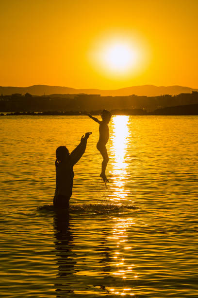 istock Father and child playing in the sea on sunset 1019001490