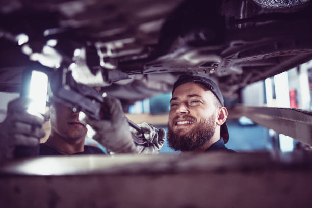 istock Car Mechanic And Apprentice Working On A Broken Car 1019009116