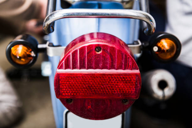 Close up scratched and old red and yellow taillight on blue motorcycle