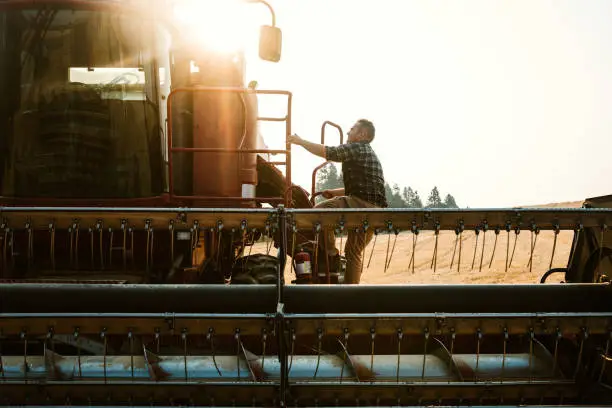 Photo of Farmer Climbing In To Combine Harvester In Idaho Wheat Field