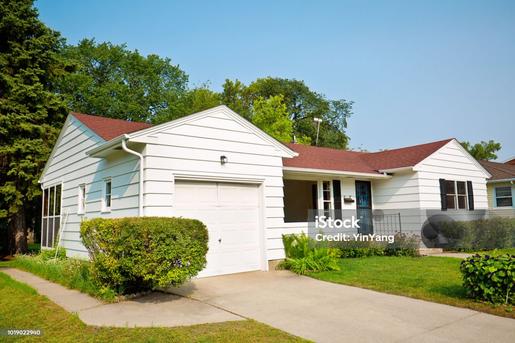 1950s United States Mid-Century Modern Bungalow House Exterior A 1950s mid-century modern bungalow style house in the mid-west of United States. The real estate featuring attached garage, picture windows and a well landscaped front yard and driveway. House Stock Photo