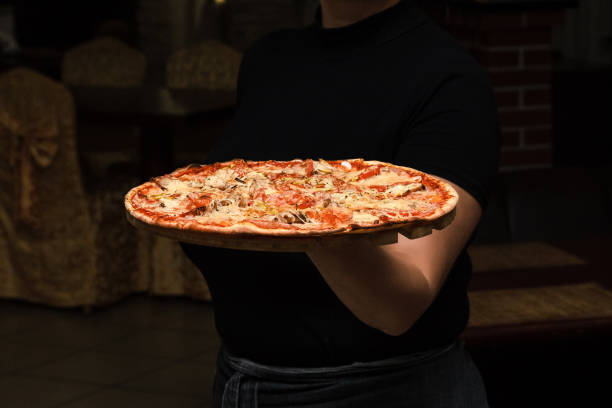 おいしいイタリアきのこピザとプレートを運ぶウェイター。レストラン グリーン テラス。イタリアン レストラン。イタリア料理。 - pizza pizzeria restaurant waiter ストックフォトと画像
