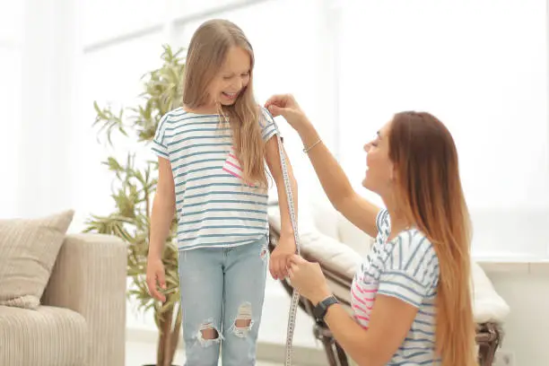 Photo of attentive mother and daughter make measurements for new clothes