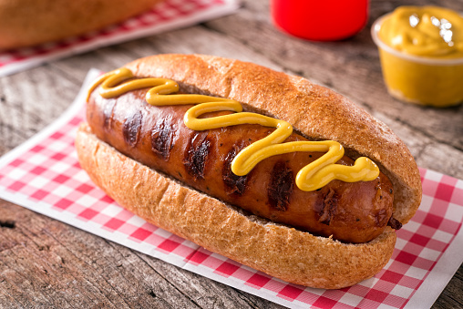 A delicious grilled smoked sausage on a roll with yellow mustard.