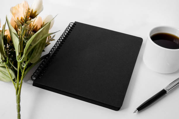 istock Black notebook with coffee cup and flower on white background. 1019048978