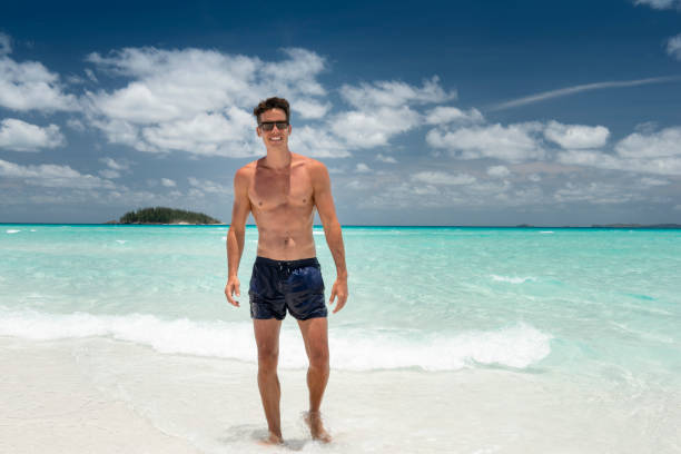 Man at the White Sand Beach, Whitsunday Islands, Queensland, Australia Handsome man enjoying this beautiful white turquoise sand beach at the famous Whitsunday Islands in Australia. Nikon D810. Converted from RAW. bathing suit stock pictures, royalty-free photos & images