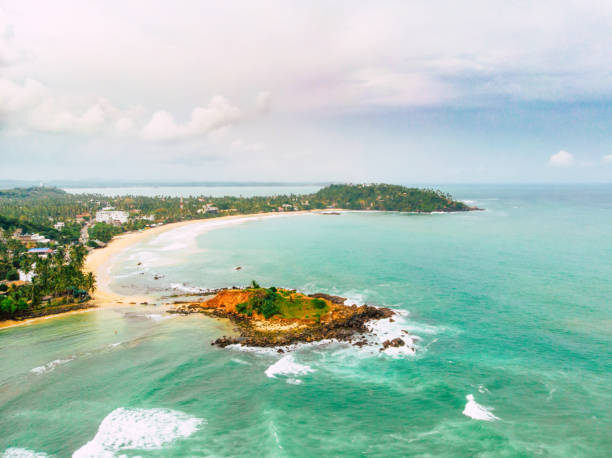 istock Flying over emerald ocean waves washing exotic white sand beach long shot 1019058442