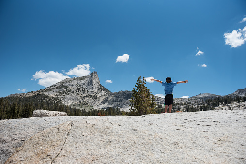 Brave and strong child embarks on a 7 miles hike up to Cathedral Peak in Tuolumne Meadows in Yosemite Valley National Park in California. Beautiful landscape with child exploring, running and playing.