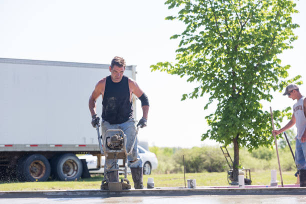 New Residential Concrete Slab with Radiant Floor Heating - Preparation and Equipment Erskine, USA - May 25, 2018: The process and equipment of preparing a private residential concrete slab foundation with a radiant floor heating system (water or propane gas). This image shows a worker operating a power screed on the freshly poured cement. Another worker is on the right of the frame. A home will be moved and placed on this slab in the near future. Driveway Installers stock pictures, royalty-free photos & images