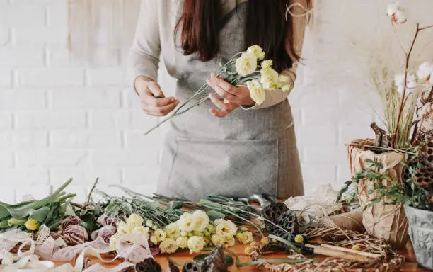 woman florist collects a bouquet decorates from different flowers
