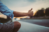 Man holding hitchhiking thumb up