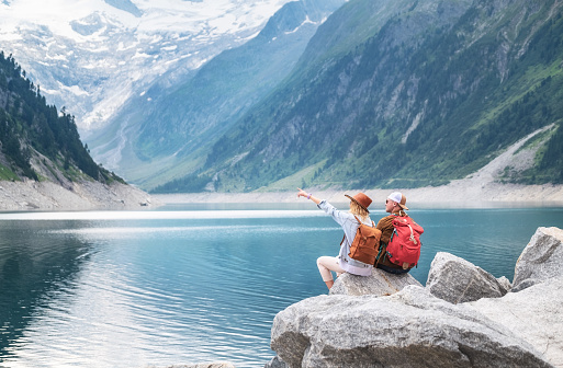 Travelers couple look at the mountain lake. Travel and active life concept with team. Adventure and travel in the mountains region in the Austria