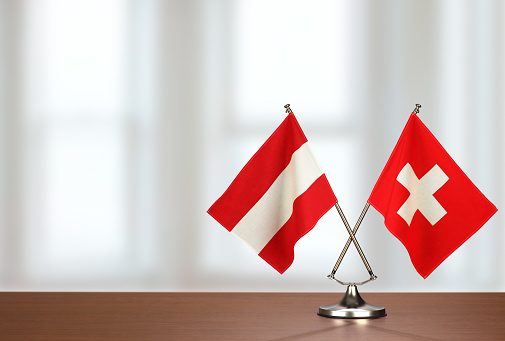 Two crossed national flags on wooden table