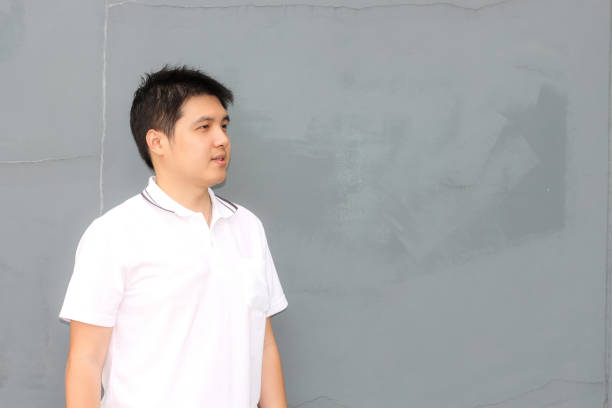 istock Asian man with white shirt over the grey wall with copy space 1019191594