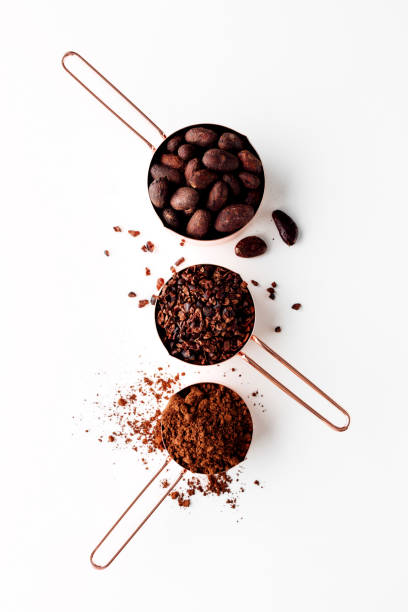 Cocoa Rose gold measuring cups of cocoa beans, cacao nips and cocoa powder on a white background, flat lay healthy food concept nib stock pictures, royalty-free photos & images