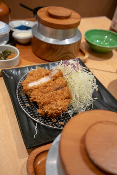 istock Closed up deep fried meat cutlet coated with flaky panko bread crumb and stuffed with cheese, Tonkatsu over metal sieve and shredded cabbage. 1019202766
