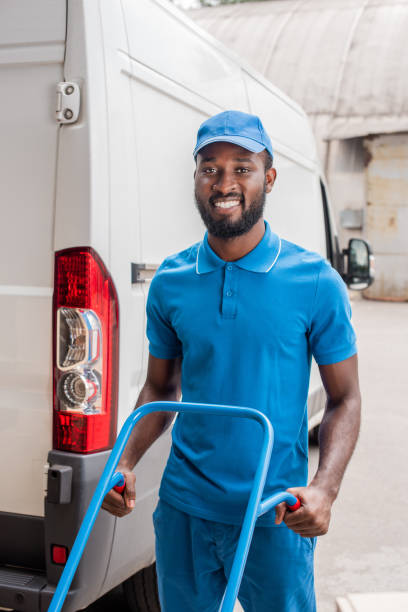 istock smiling african american courier with cart looking at camera near van 1019214062