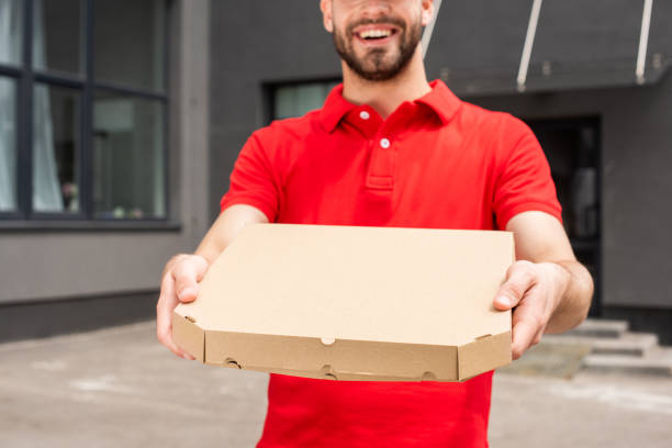 istock cropped image of delivery man holding box with pizza 1019217184