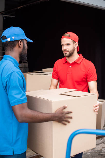 istock multicultural delivery men in red and blue uniform with cardboard boxes 1019217500