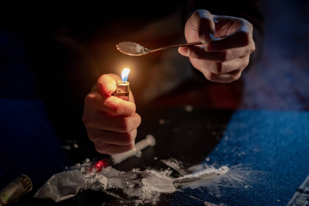 männliche junkie hand heroin dosis mit löffel und zigarettenanzünder für schmelzen, spritze für die injektion vorbereitet. harte drogen-überdosis und sucht-konzept - narcotic teenager cocaine drug abuse stock-fotos und bilder