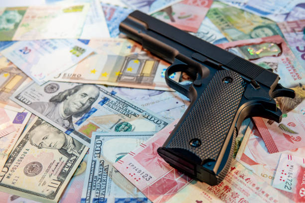 각종 국제 지폐에 검은 총. 불법 무기 밀매 개념 - currency crime gun conflict 뉴스 사진 이미지