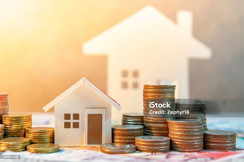 Real estate or property investment. Home mortgage loan rate. Saving money for retirement concept. Coin stack on international banknotes with house model on table. Business growth background House Stock Photo