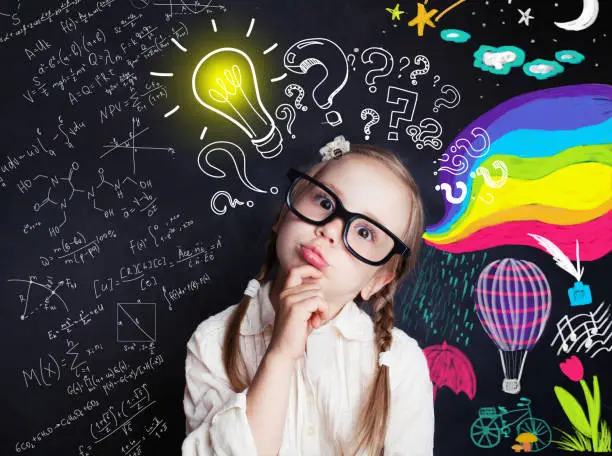 Photo of Pensive child school student with yellow lightbulb and school and childhood supplies design elements. Child ideas and development concept