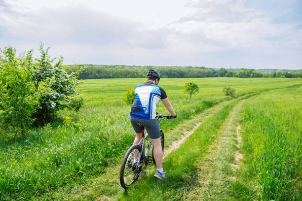 istock man riding bicycle by trail in green barley field. copy space 1019220778