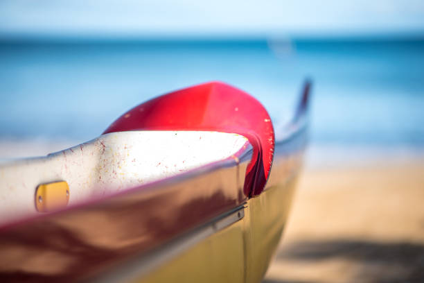 Outrigger Canoe Facing Ocean on Maui The bow of an outrigger waits on a south Maui beach, with the ocean in the soft background. outrigger stock pictures, royalty-free photos & images
