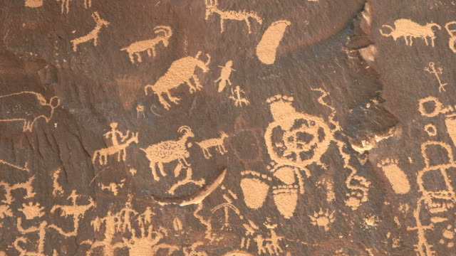zoom in shot on a drawing of a human figure hunting sheep at newspaper rock