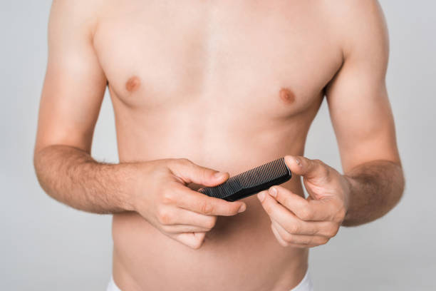 istock partial view of shirtless man holding comb in hands isolated on grey 1019238762