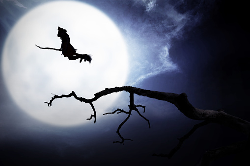 Silhouette of witch flying with broomstick on the night