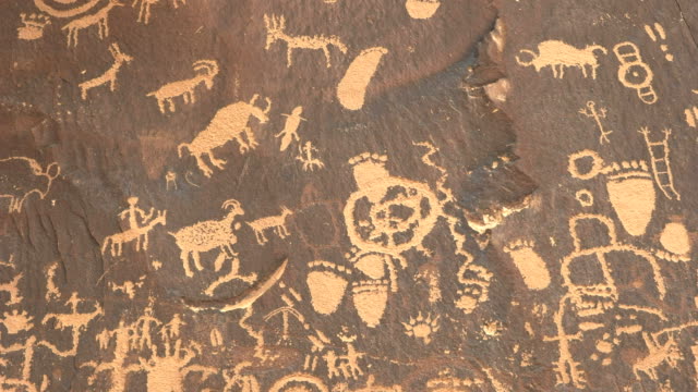 tilt down shot of ancient american indian drawings on newspaper rock in utah