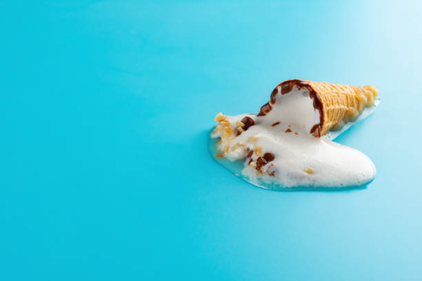istock mini Vanilla flavor ice cream cone in a melting process on blue background 1019248712