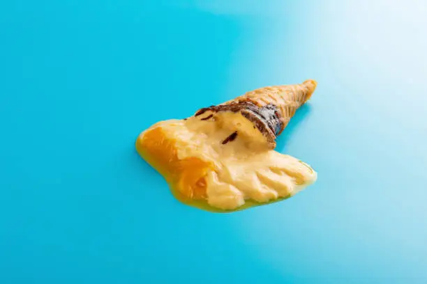 mini mango or orange flavor ice cream cone melting on blue background