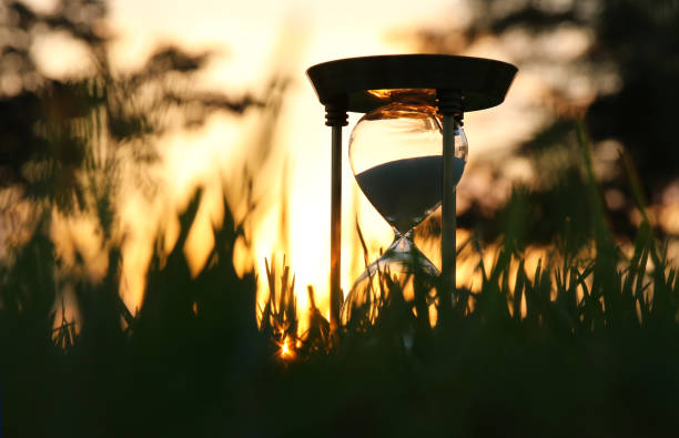 istock Hourglass in the grass time during sunset. vintage style. 1019265724