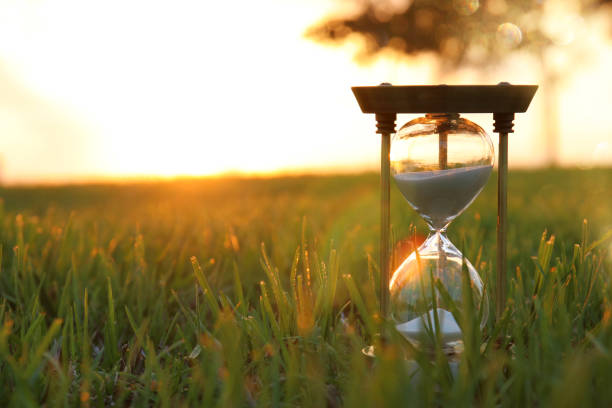 istock Hourglass in the grass time during sunset. vintage style. 1019265738