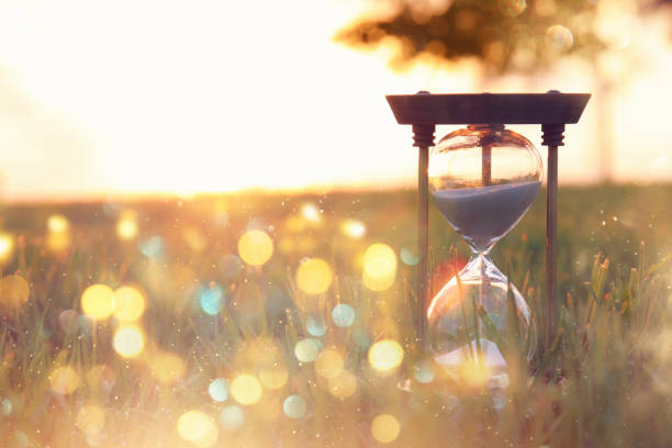 istock Hourglass in the grass time during sunset. vintage style. 1019265812